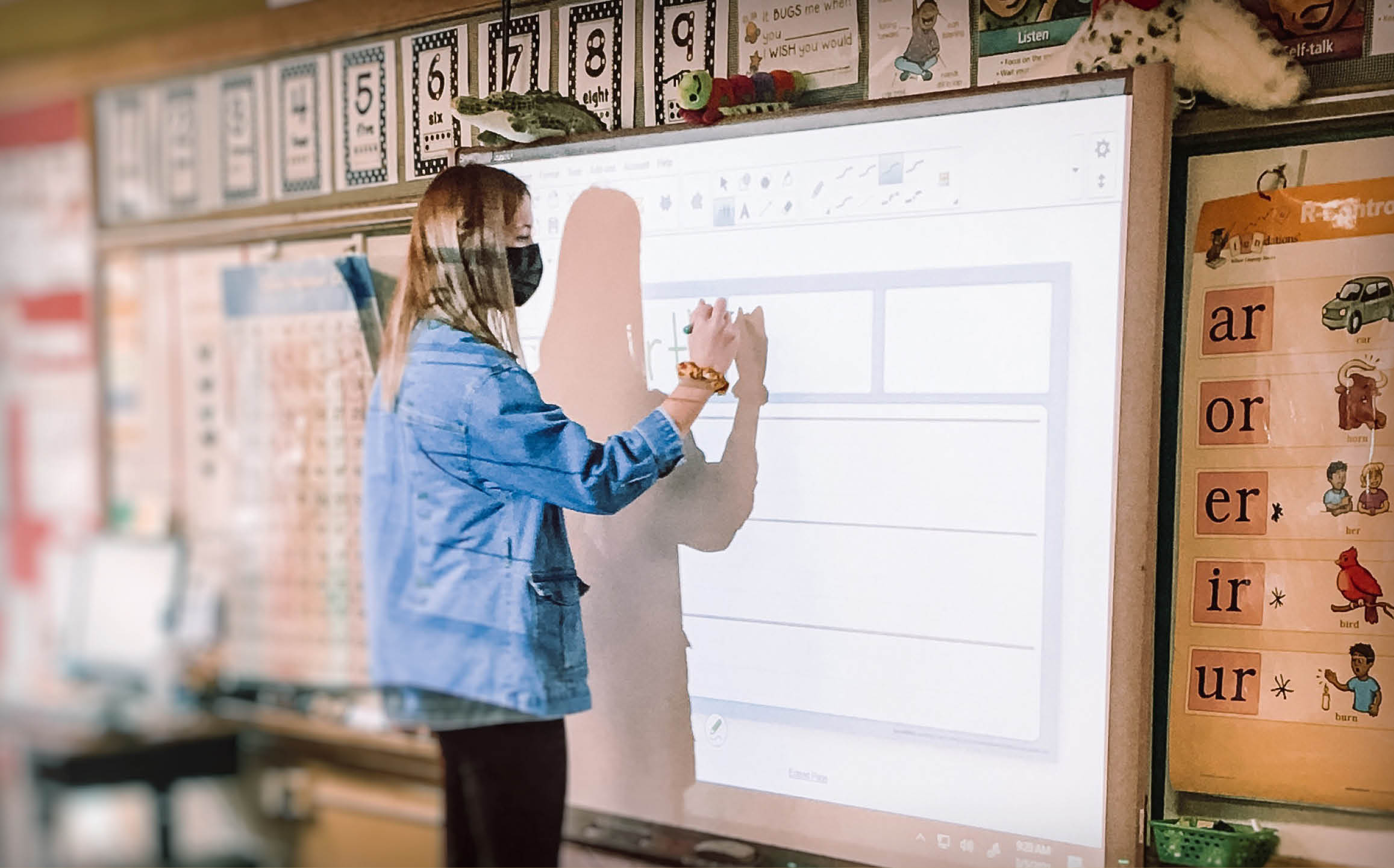 A teacher writing on a smart board in a school