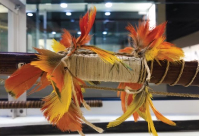 A bow wrapped in string with feathers wrapped around it.
