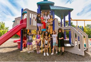 site leader and students smile on playground