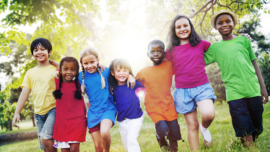 group of children smiling and walking through grass
