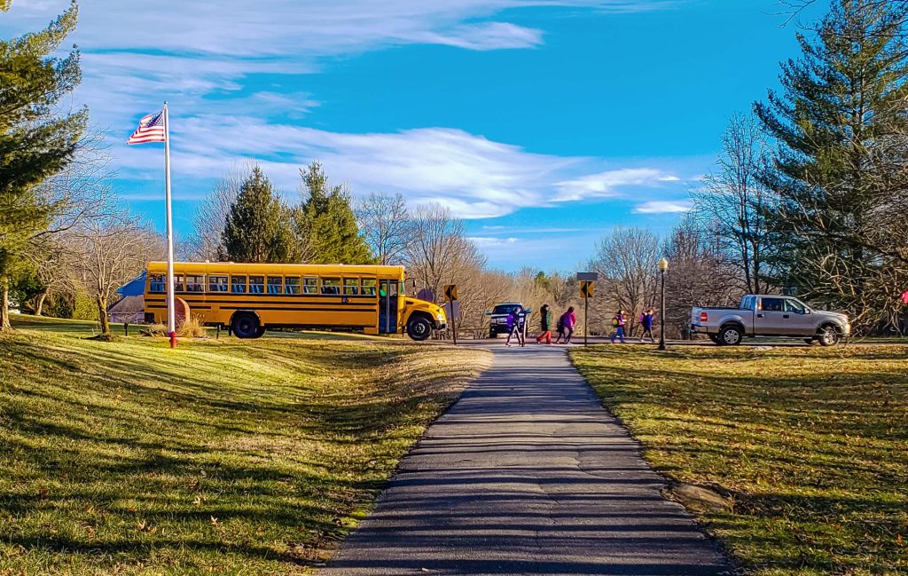 View of school bus letting children out on suburban street; blue sky in the background