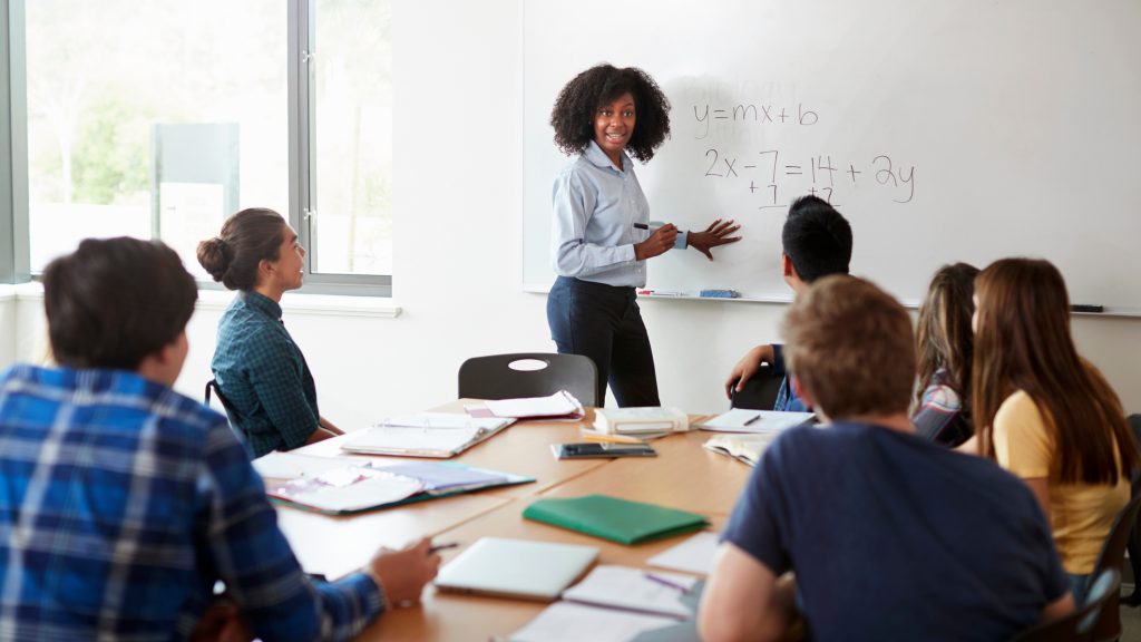 math teacher working on problem in front of classroom