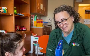 A child life specialist smiles at a patient