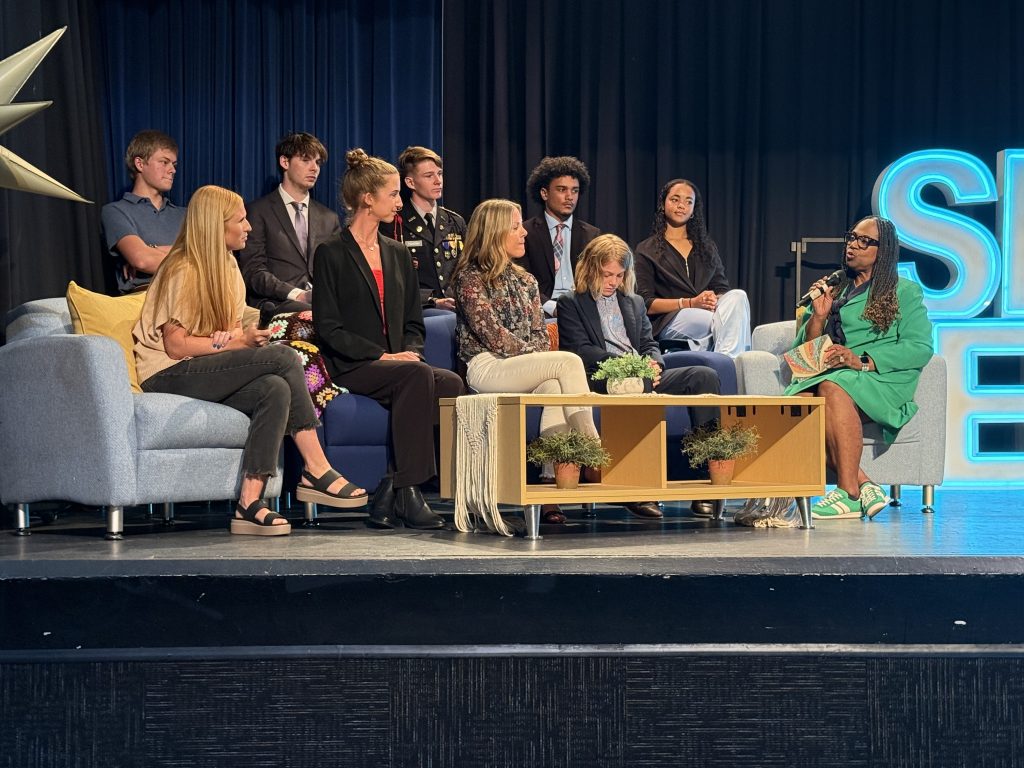 Several people on a stage listening to Dr. Grenita Lathan 