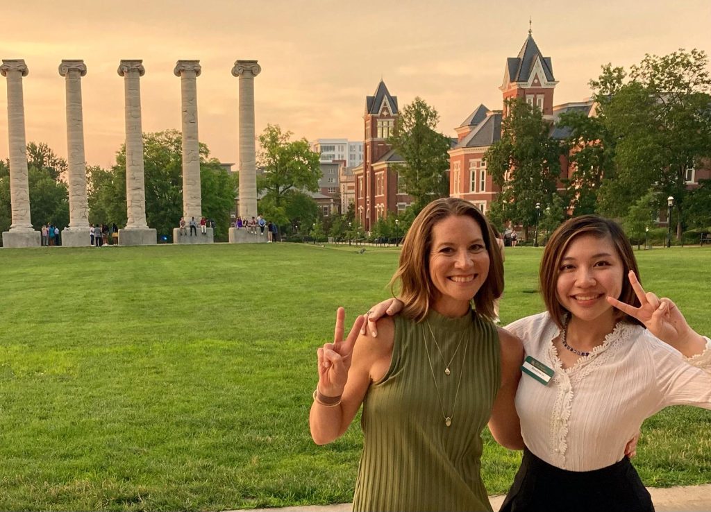 Two smiling women in front of historic columns on the University of Missouri - Columbia campus.