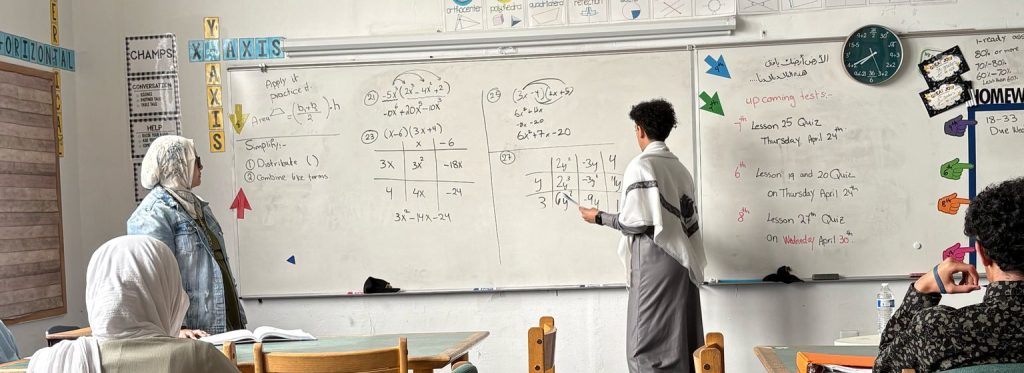 Students in front of a whiteboard working on math.
